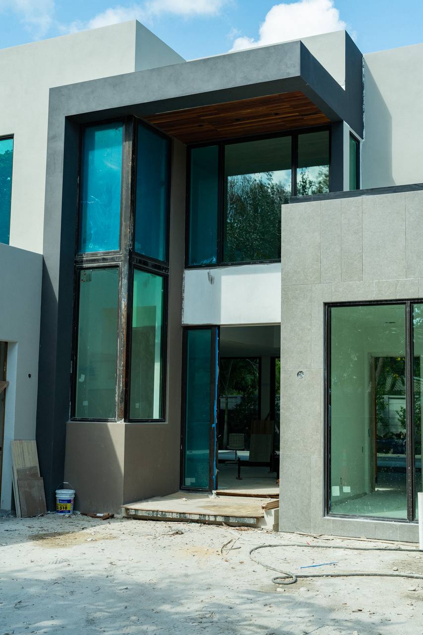 Newly constructed modern home with geometric stucco facade and floor-to-ceiling glazing
