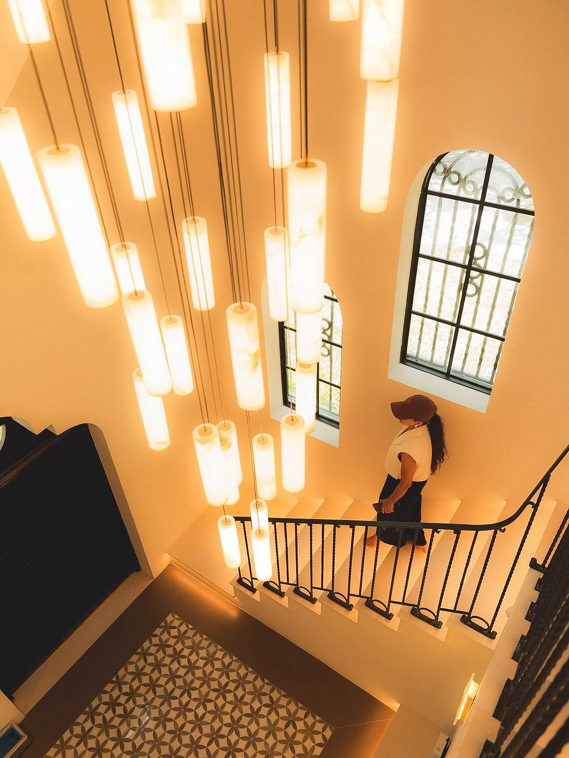 Sculptural pendant lights illuminating an arched-window staircase