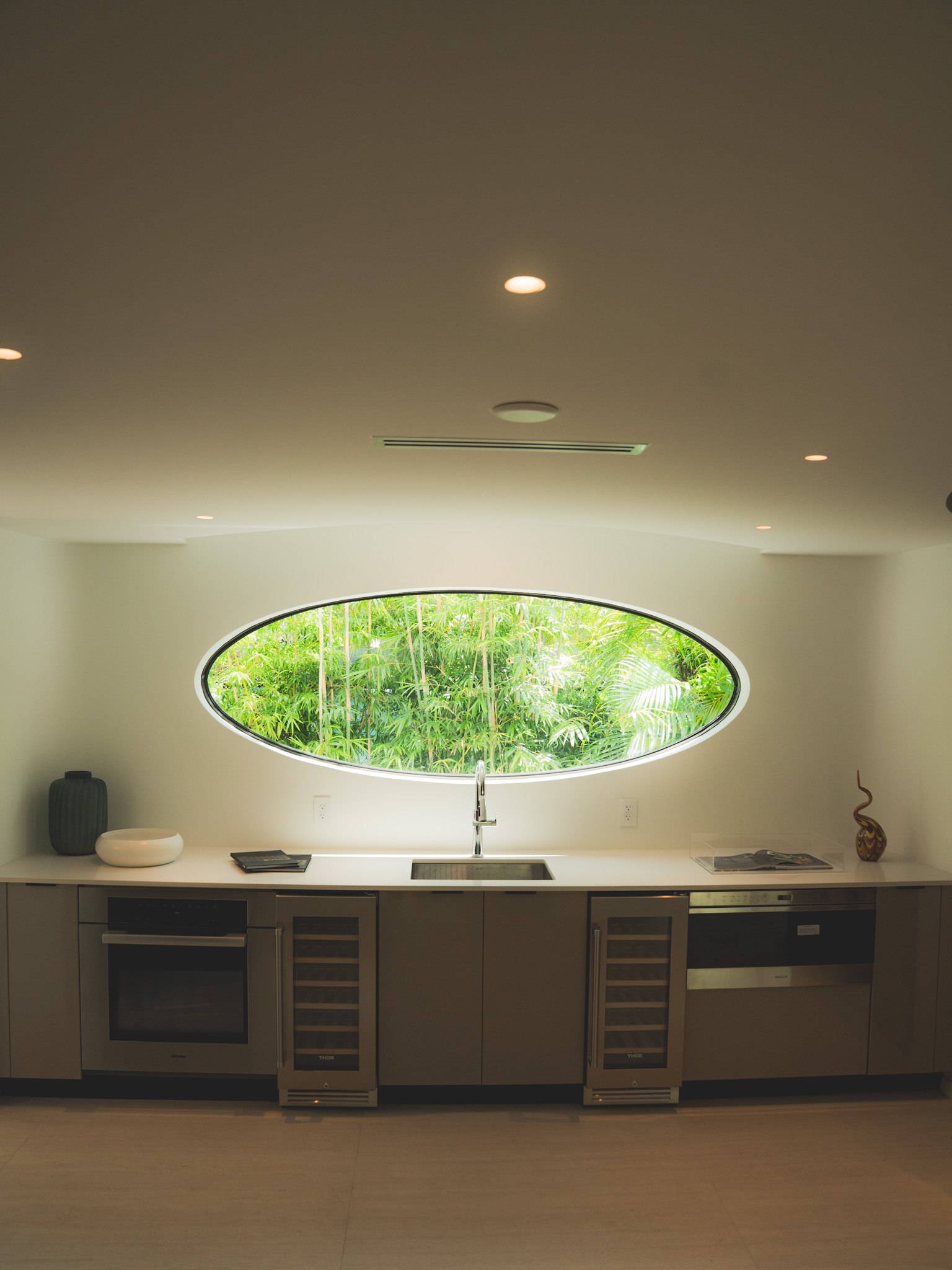Contemporary kitchen with an oval window overlooking tropical greenery